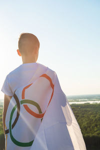 Rear view of man standing by sea against clear sky