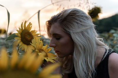 Close-up of young woman smelling sunflower at farm