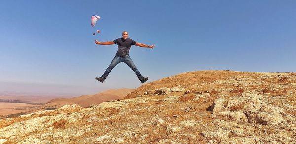 Man standing on rock against sky