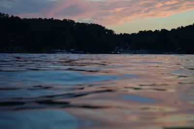 Surface level of lake against sky at sunset