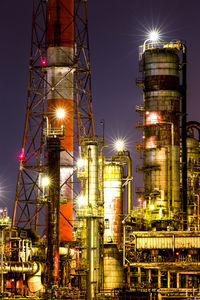 Low angle view of illuminated oil industry against sky at night