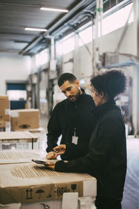 Female entrepreneur discussing with male colleague over digital tablet at warehouse