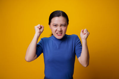 Portrait of teenage girl standing against yellow background