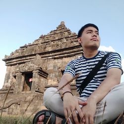 Low angle view of man sitting against sky