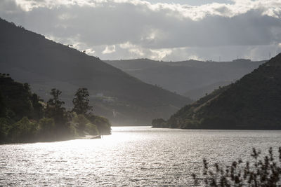 Scenic view of lake by mountains against sky