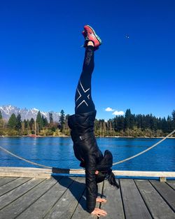 Man standing by lake against clear blue sky