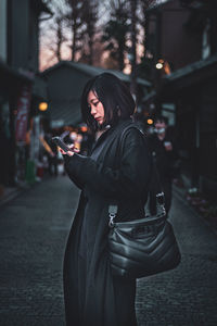 Side view of woman using mobile phone outdoors