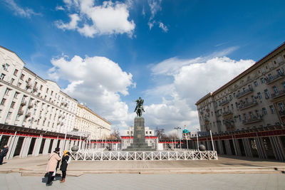 Statue in city against cloudy sky