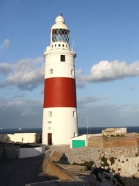 Lighthouse by sea against sky