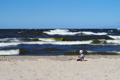 Boy on beach against clear sky