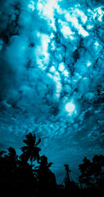 Low angle view of silhouette trees against blue sky