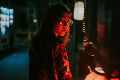 Portrait of young woman standing outdoors at night