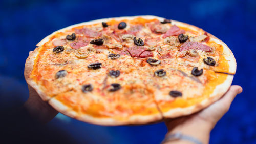 Close-up of hand holding pizza