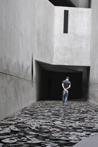 Rear view of woman standing on footpath against building