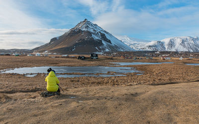Full frame view of a photographer setting up for panoramic snow covered mountain range landscape