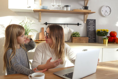 Woman using phone while sitting on table