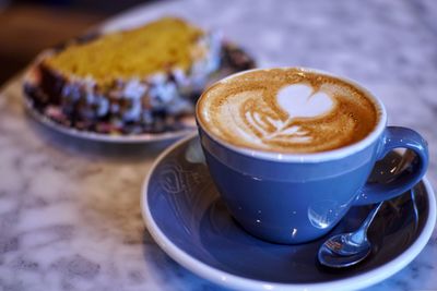 Close-up of cappuccino with cake on table