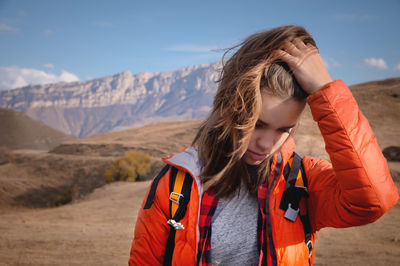 Attractive jewish young woman with a backpack in the mountains. runs her hand through her hair while