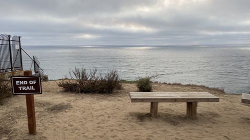 Information sign on beach against sky
