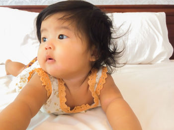 Portrait of cute girl eating while relaxing on bed at home