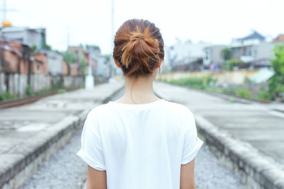 Rear view of woman standing on railroad track