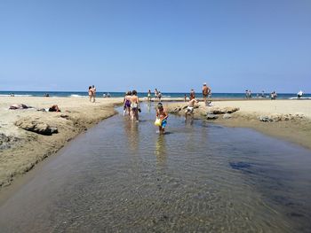 People on beach against clear sky