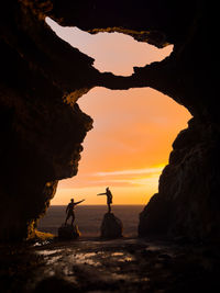 Silhouette woman standing on rock against sky during sunset