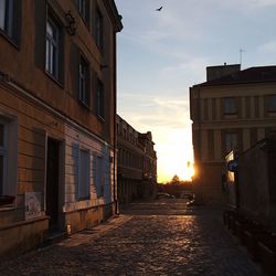 Street amidst buildings against sky during sunset