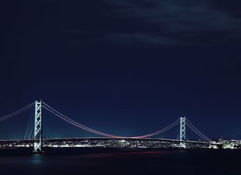 Illuminated akashi strait bridge over sea against clear sky at night