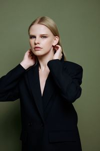 Portrait of young businesswoman standing against yellow background