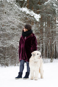 Beautiful young woman with her south russian shepherd dog on a background of winter forest.