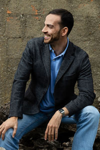 Young man sitting against wall