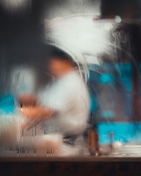 Blurred motion of woman seen through glass window
