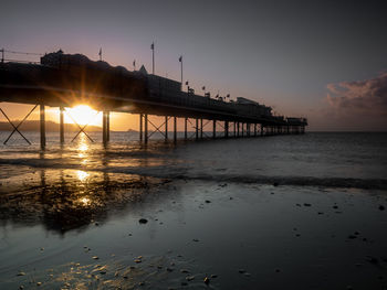 Pier over sea against sky during sunset