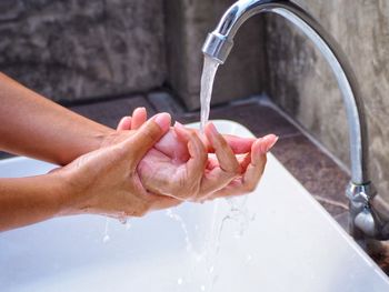 Cropped hand of woman washing hands in bathroom