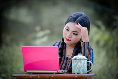 Young woman using laptop while sitting on table