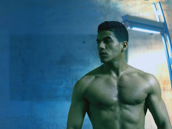 Shirtless man standing against wall