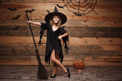 Girl with hand on hip standing against wooden wall during halloween