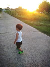 Rear view of boy walking on road