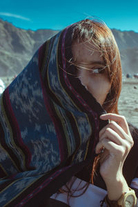 Portrait of young woman drinking water from mobile phone outdoors