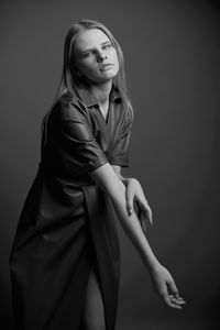 Portrait of young woman standing against black background