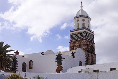 Low angle view of bell tower against cloudy sky