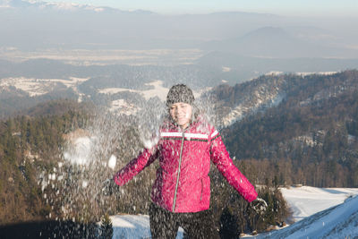 Woman playing with snow against mountains