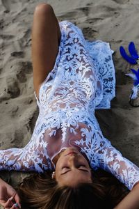 High angle view of young woman lying on sand at beach