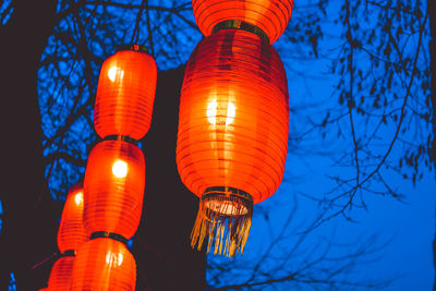 Low angle view of illuminated lanterns against sky at dusk