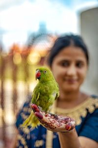 Portrait of woman holding bird perching on hand