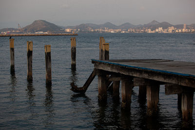 Wooden posts in sea against sky