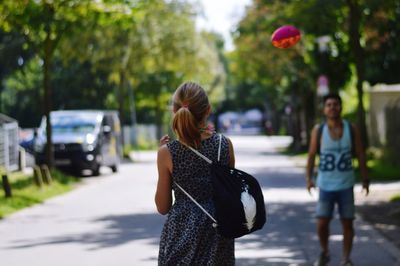 Teenage girl walking on road with man standing in background