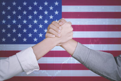 Cropped image of people holding hands against russian and american flags