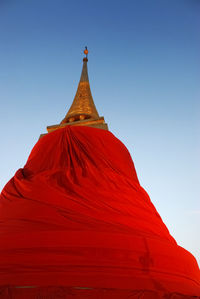 Low angle view of stupa covered in red fabric against clear sky